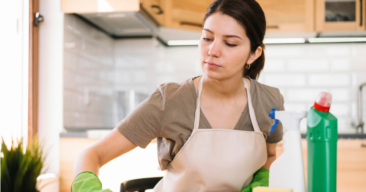 A cleaner in an apron at work in a kitchen