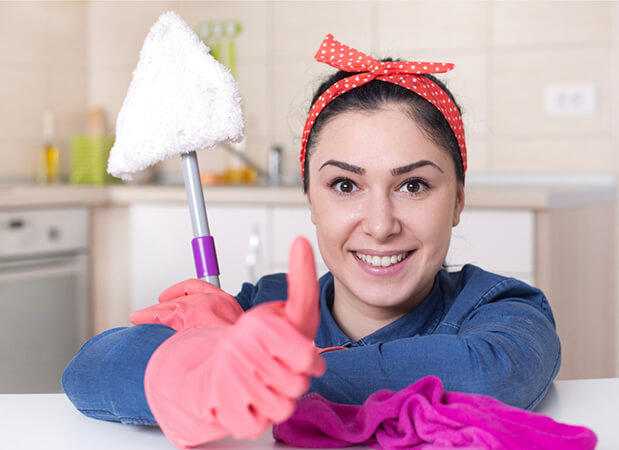 A smiling cleaner with a mop giving a thumbs up
